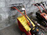 several lawn mowers are lined up against a wall in a garage