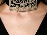 a close up of a woman wearing a black top and a gold choke