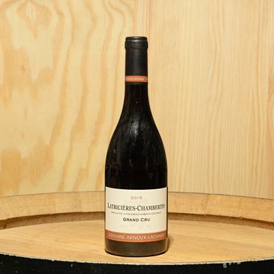 a bottle of wine sitting on top of a barrel