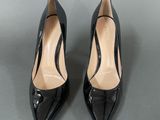a pair of black high heeled shoes on a gray surface