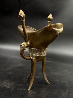 brass statue of a fish holding a spear on a black background