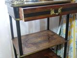 a small table with a shelf on it in front of a curtain