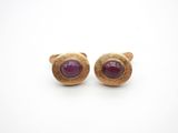 a close up of a pair of gold earrings with a purple stone