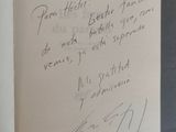 un livre ouvert, sur lequel est posée une note manuscrite, posé sur une table