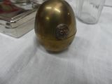 a golden egg sitting on a white table with a silver container