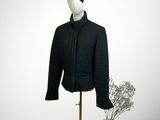 une veste posée sur un mannequin, avec un vase de fleurs en arrière-plan