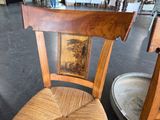 a wooden chair with a painting on the back of it