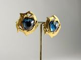 pair of gold and blue glass earrings on a stand