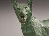 bronze statue of a dog with open mouth standing on a white surface