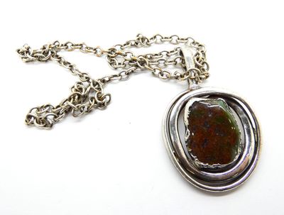 une chaîne en argent avec un pendentif orné d'une pierre, sur un fond blanc