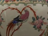 a large vase with a bird on it sitting on a table