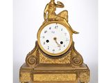 une horloge en or sur laquelle est assis un homme