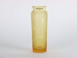 un vase jaune posé sur une surface blanche