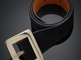 une ceinture en cuir noir avec une boucle argentée sur fond sombre