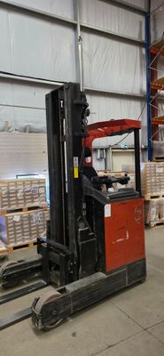 un chariot élévateur dans un entrepôt où se trouvent des palettes et des cartons
