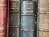 several old books are lined up in a row on a shelf
