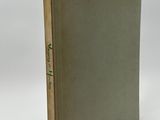 un livre à la couverture verte posé sur une surface blanche