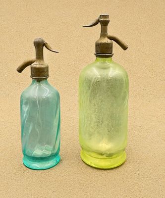 deux bouteilles en verre vertes et bleues munies d'un robinet en métal sur le dessus