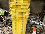 un seau jaune auquel sont suspendues des chaînes, à côté d'un tas de matériel de chantier