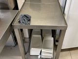 table en acier inoxydable sur laquelle sont posées des assiettes et des bols, dans une cuisine professionnelle