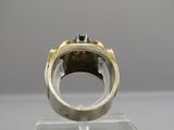 une photo d'une bague en argent et en or posée sur un socle transparent