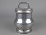 an old silver metal container with a handle on a gray surface