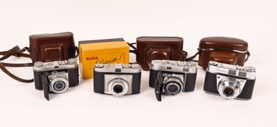 several old cameras are lined up in a row on a white surface