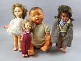 three dolls sitting next to each other on a gray surface