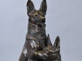 bronze sculpture of two dogs sitting on top of each other