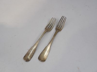 une paire de fourchettes plaquées argent posées sur une surface blanche