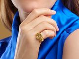 a woman in a blue shirt with a gold ring on her finger