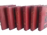 six livres rouges alignés sur une surface blanche