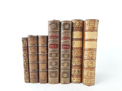 several old books are lined up in a row on a white surface