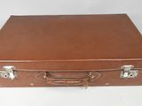 une vieille valise marron posée sur une table blanche