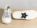 sneakers with black stars on them on a wooden surface