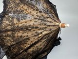 un parapluie en dentelle noire posé sur une surface blanche