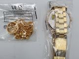 a gold watch and a gold chain on a white table