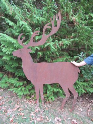 un homme qui se tient à côté d'un cerf en métal