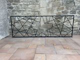 a black iron fence on a brick floor near a stone wall