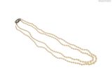 un collier de perles blanches avec un fermoir en argent sur fond blanc