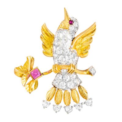 une photo d'une broche en forme d'oiseau en or et diamants, ornée d'une pierre rose