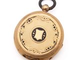 an image of a gold pocket watch with a black and white design