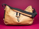 a close up of a gold purse with a black strap