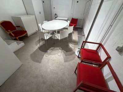 une table blanche et des chaises rouges dans une petite pièce