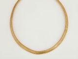 gros plan d'un collier en or sur une surface blanche