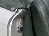 a close up of a green leather jacket on the back of a white car