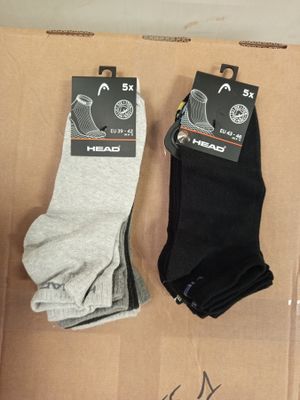 Deux paires de chaussettes noires et grises sont posées sur une boîte en carton