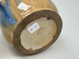 a brown and blue vase sitting on a white surface