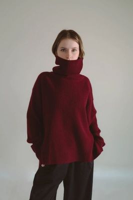 the woman is wearing a red sweater and black pants