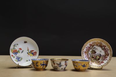 three cups and saucers sitting on a wooden table with a black background